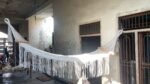Macrame hammock with wooden spreader bars and long fringes hanging indoors