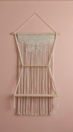 Handwoven cotton macrame shelf wall hanging on a pink wall