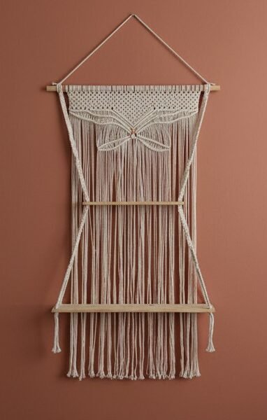 ProKnots macrame wall hanging shelf with butterfly design and two wooden shelves on a terracotta wall