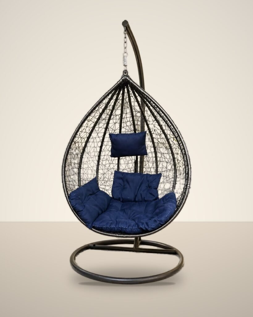 Black HDPE wicker hanging egg chair swing with stand and navy blue cushions, studio background
