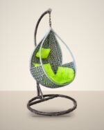 Grey HDPE wicker hanging teardrop chair swing with stand and lime green cushions, studio background